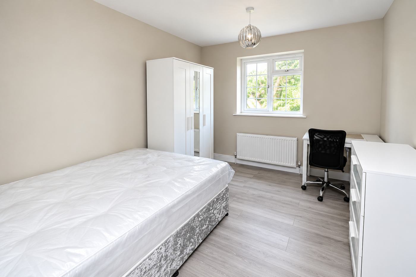 Bedroom after an end of tenancy clean, with a spotless laminate floor, clear desk and empty wardrobe